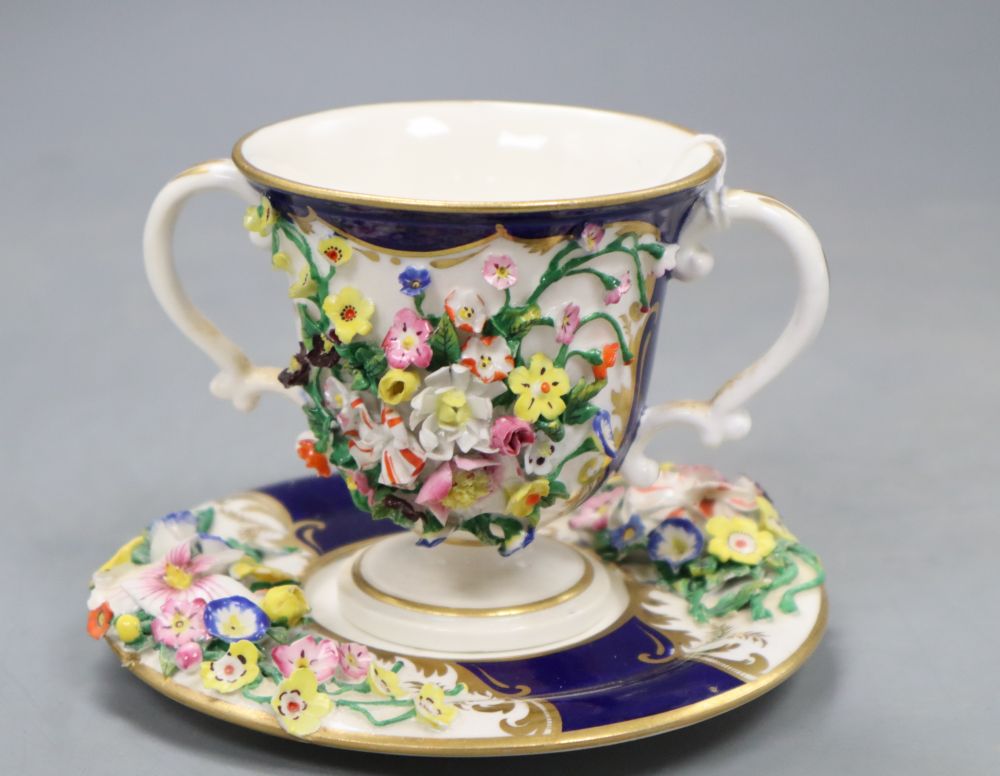 A Bloor Derby floral encrusted two handled cup and saucer, red printed factory mark